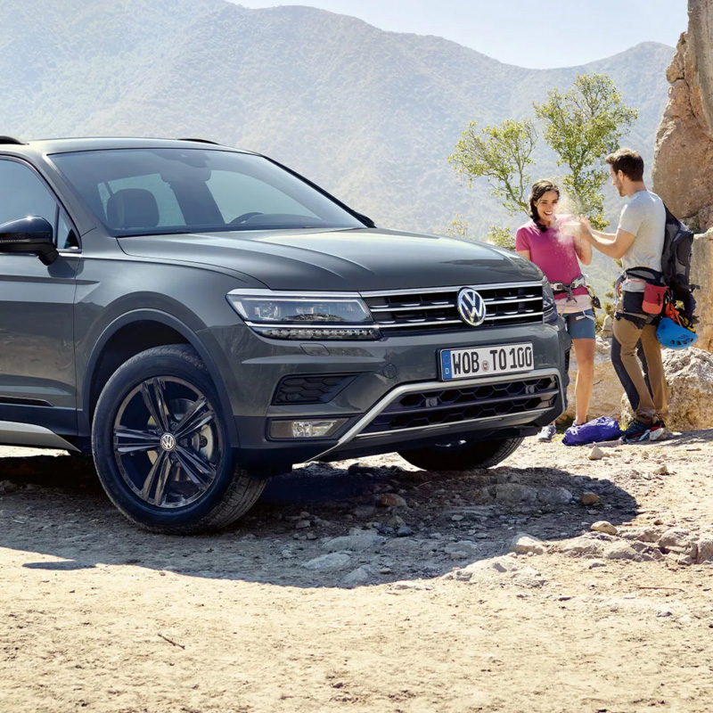 Volkswagen Tiguan w górach, obok wspinacze szykujący się na wyprawę