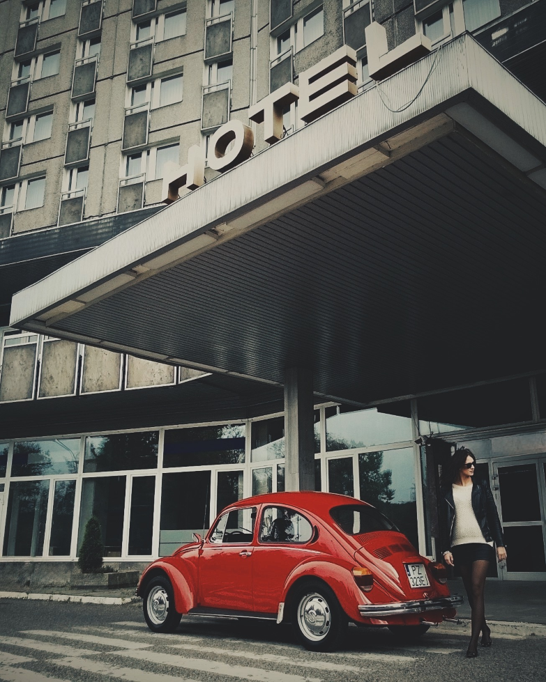 Czerwony Volkswagen Beetle stoi przed budynkiem.