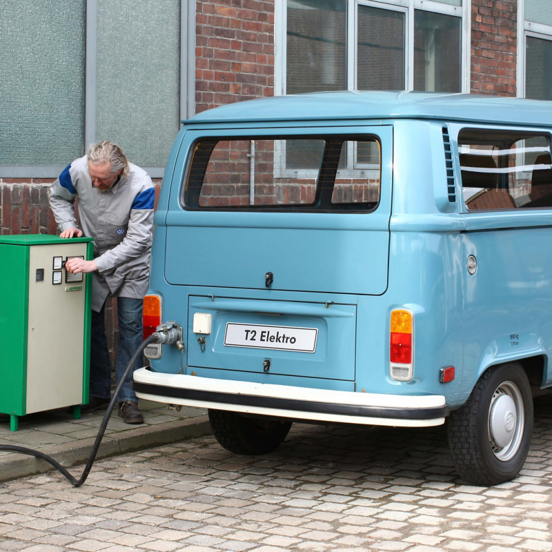 A vintage T2 Elektro van being charged in a cobbled street