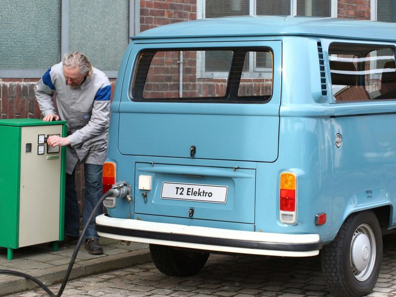 A vintage T2 Elektro van being charged in a cobbled street