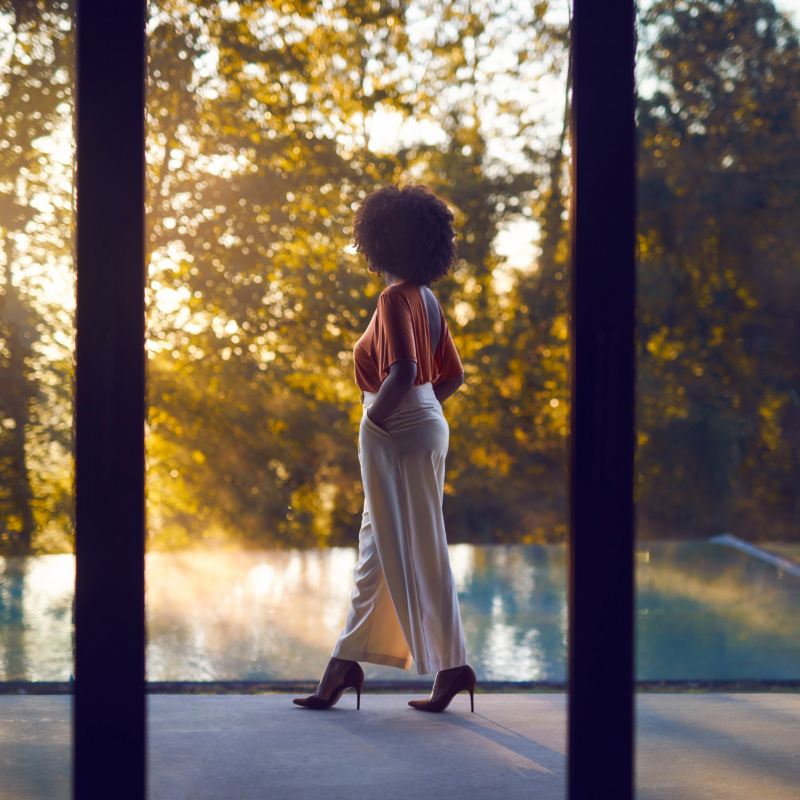 A lady walking besides a swimming pool looking out into the countryside