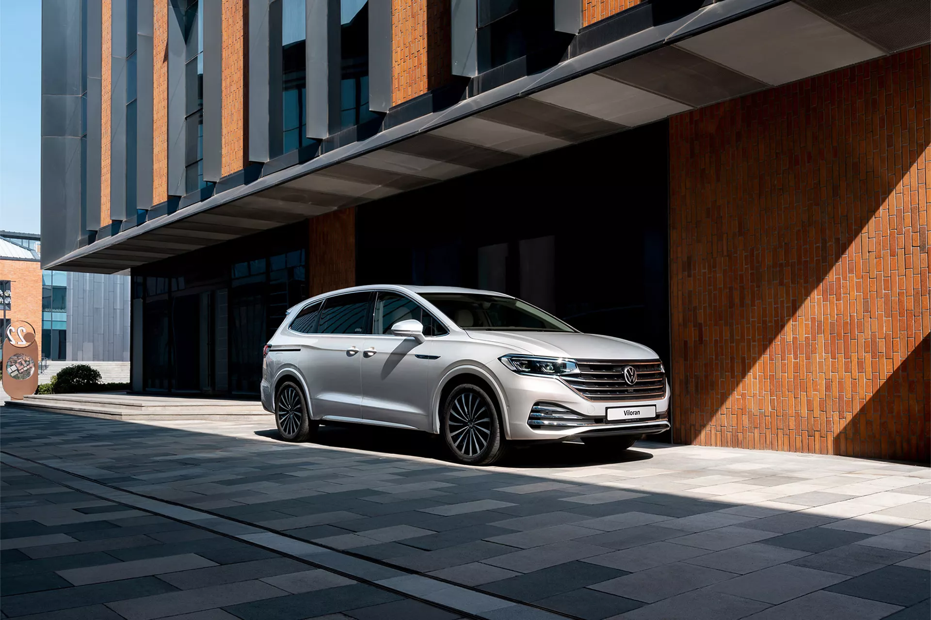 Volkswagen Viloran màu bạc bên công trình kiến trúc hiện đại