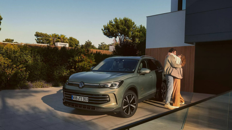 A couple hugging by a parked Volkswagen vehicle