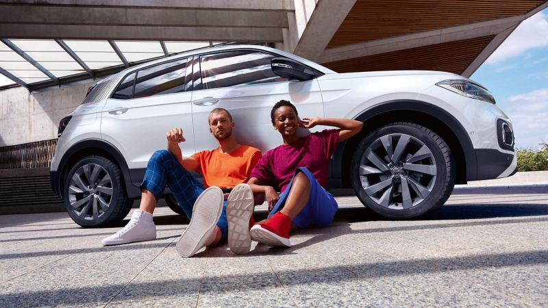 Couple sat on the ground leaning against their car