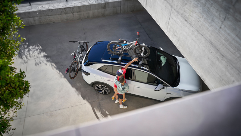 A father carrying his son whilst touching a bike rack on a car roof