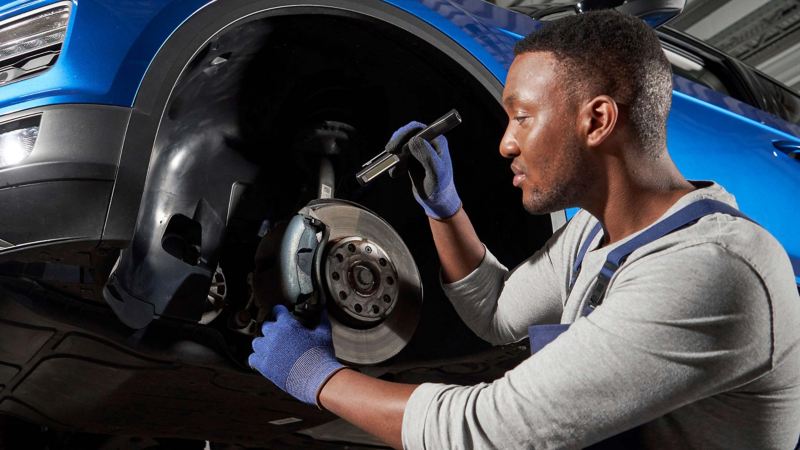 A VW service agent examining a brake pad of a car