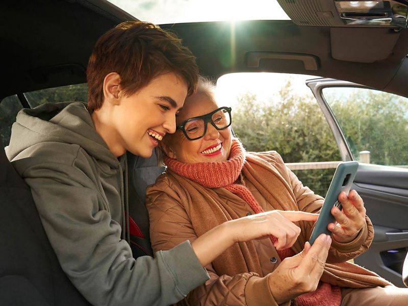 Two women inside a VW car and looking at a phone