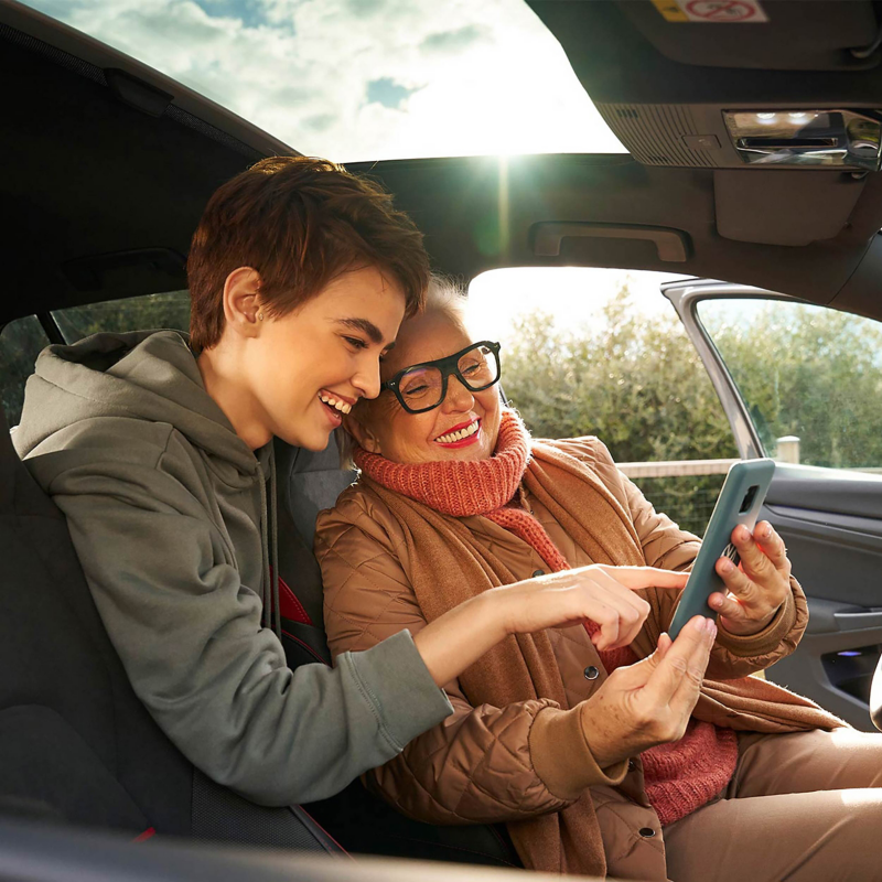 Two women inside a VW car and looking at a phone