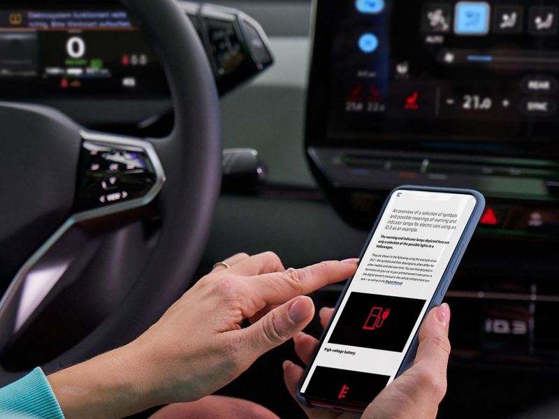 Close-up VW cockpit, in the foreground a smartphone with information about a warning light