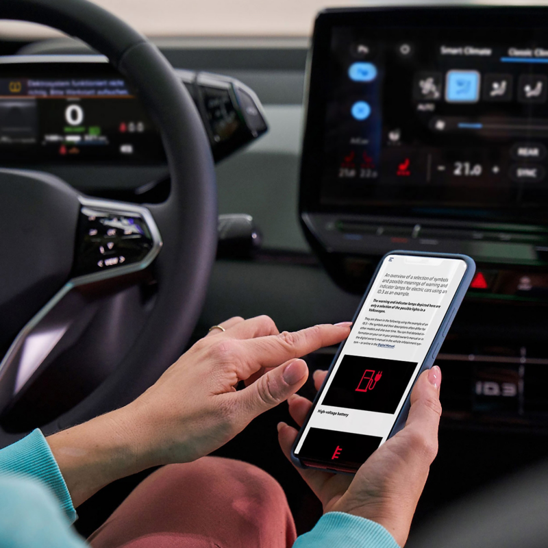 Close-up VW cockpit, in the foreground a smartphone with information about a warning light