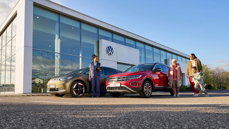 A family beside a T-Roc outside a dealership being assisted by a VW employee
