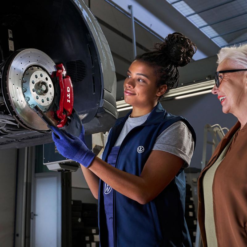 Volkswagen service employee with a customer looking at the brakes of a VW car