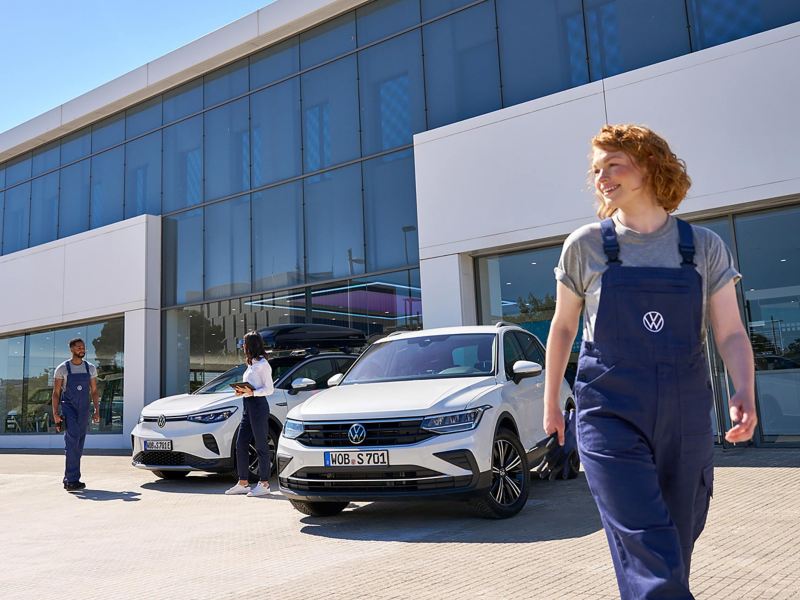 A Volkswagen service agent walking away from 2 VW cars and 2 colleagues