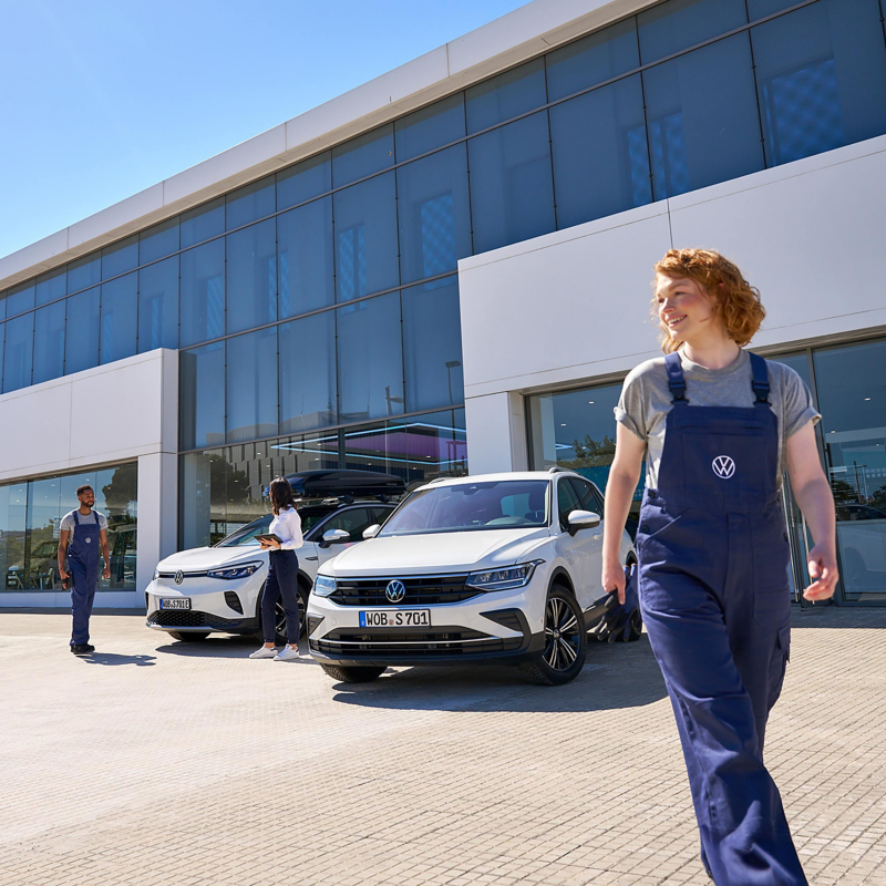 A Volkswagen service agent walking away from 2 VW cars and 2 colleagues