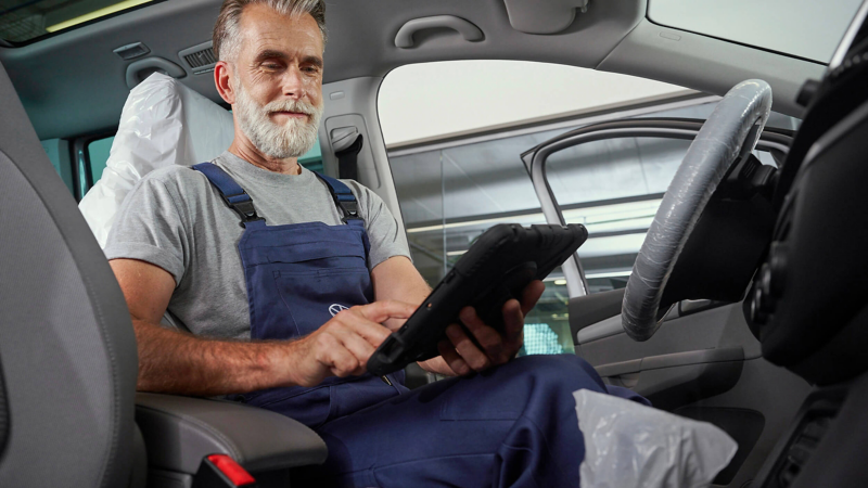 VW service employee sitting in a VW, inspecting the car