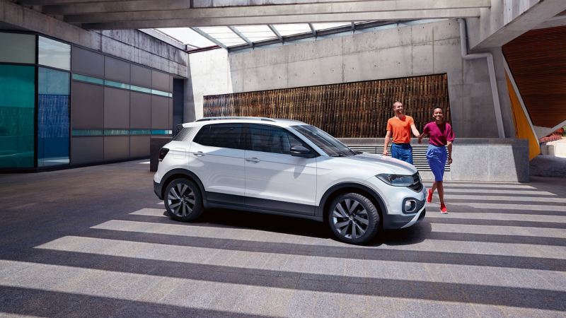 A couple walking together towards their parked VW Tiguan