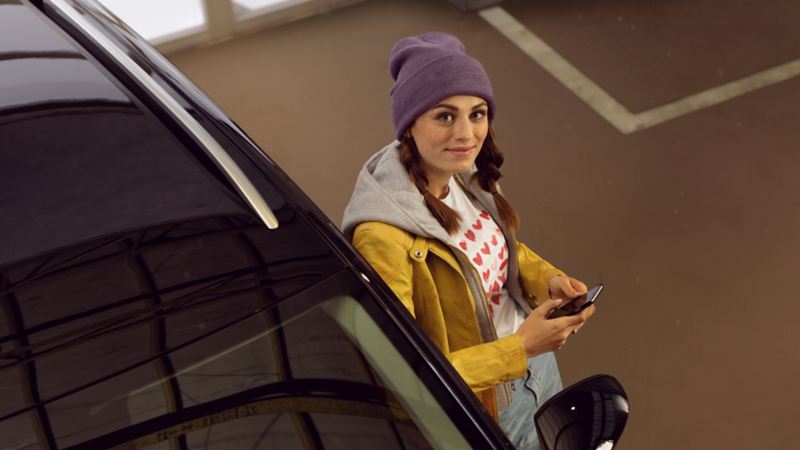 A smiling customer leaning on a Volkswagen car