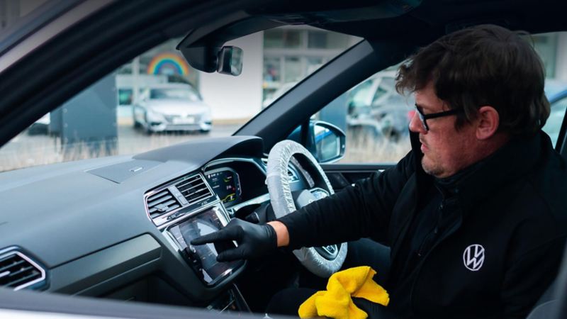 A service employee sits inside a VW pressing on the infotainment screen