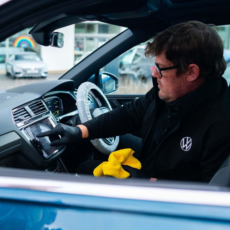 A service employee sits inside a VW pressing on the infotainment screen