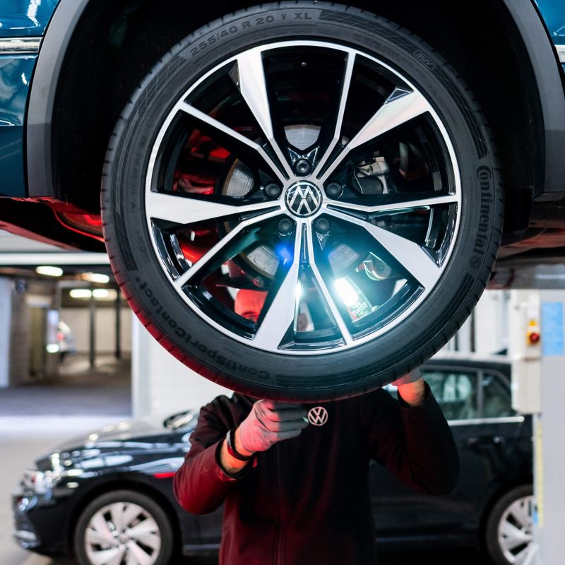 A VW technician inspecting a tyre with a light