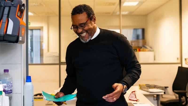 A VW service employee smiling holding paperwork