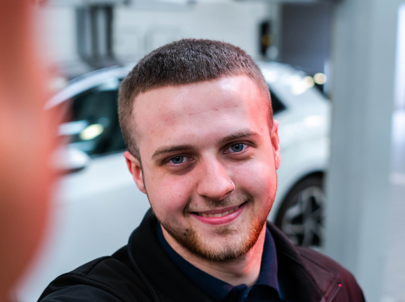 A VW service employee smiling holding paperwork