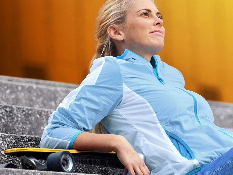 woman sitting on steps with a skateboard