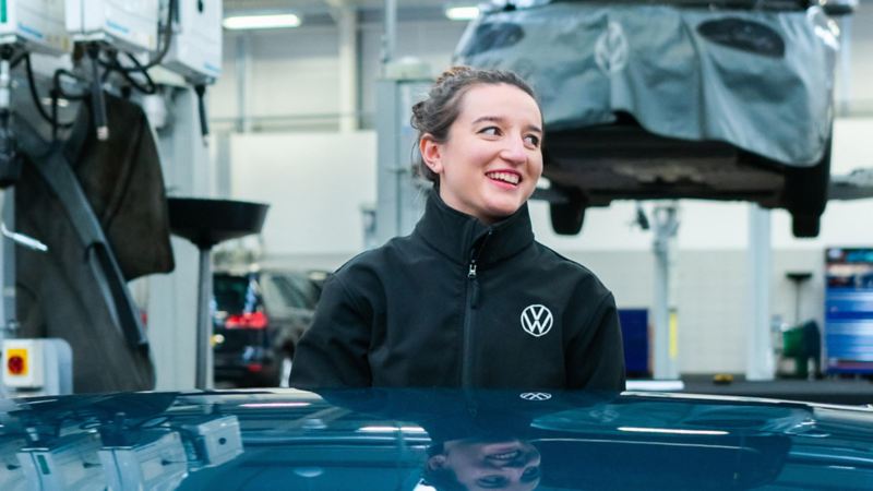 A technician standing in front of a VW with the bonnet raised