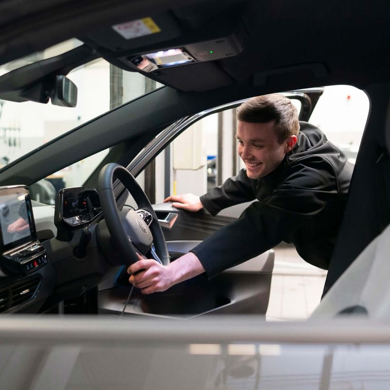 A VW service employee leans into an ID.3 holding the steering wheel