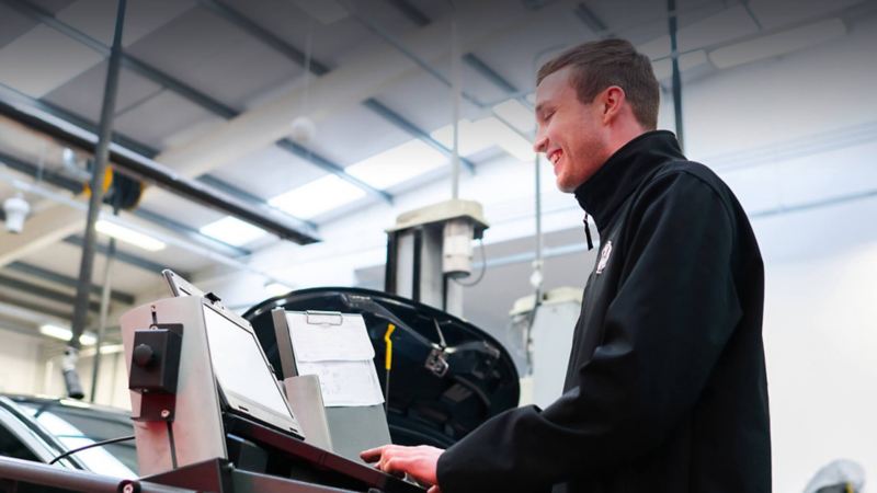 A technician typing into a computer with paperwork on a clipboard next to them