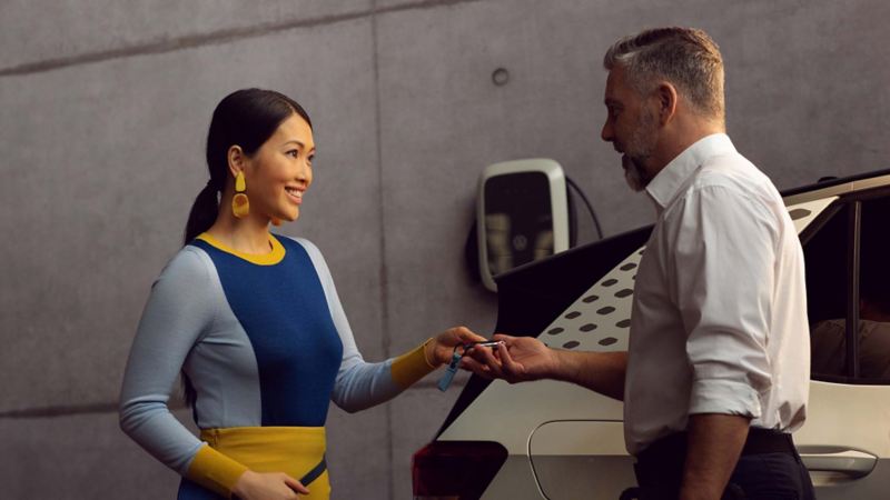 A customer hands over the vehicle key for her EV to the VW service employee