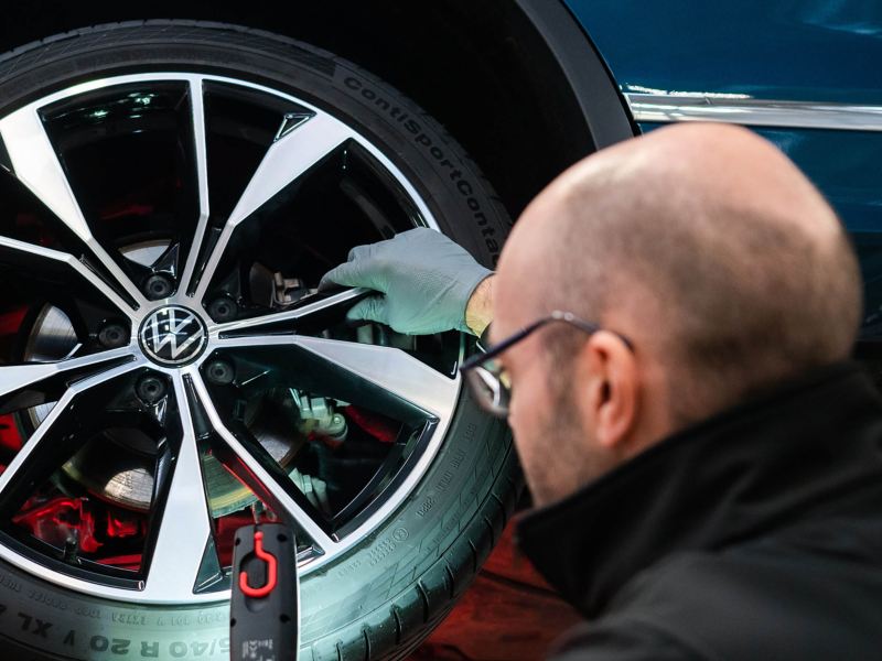 A VW technician inspecting a tyre with a light