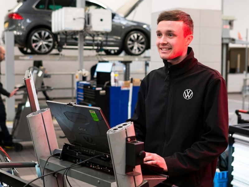 A VW technician typing into a computer in a workshop