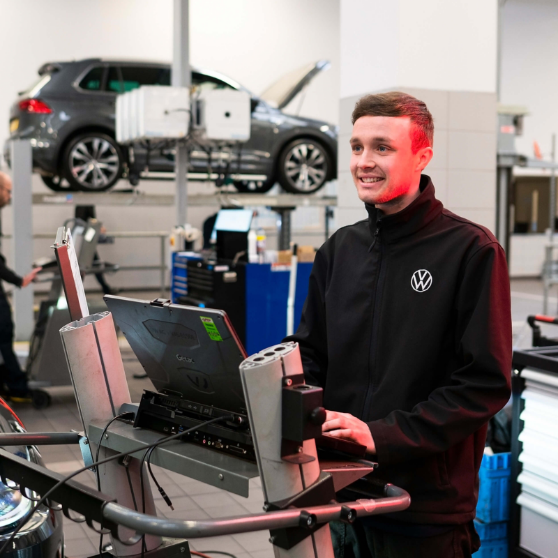 A VW technician typing into a computer in a workshop