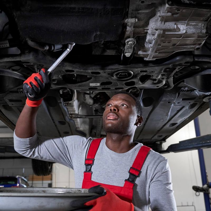 Man wearing red overalls and gloves working on a car