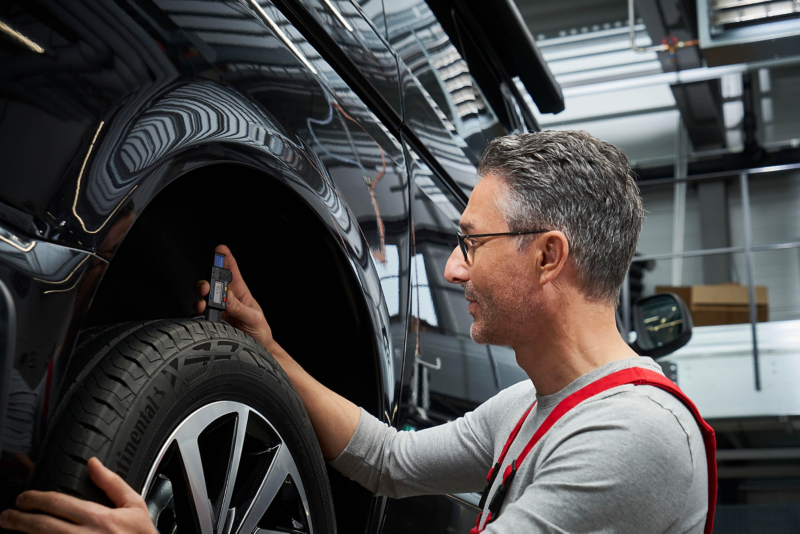 Mechanic taking tyres off shelf
