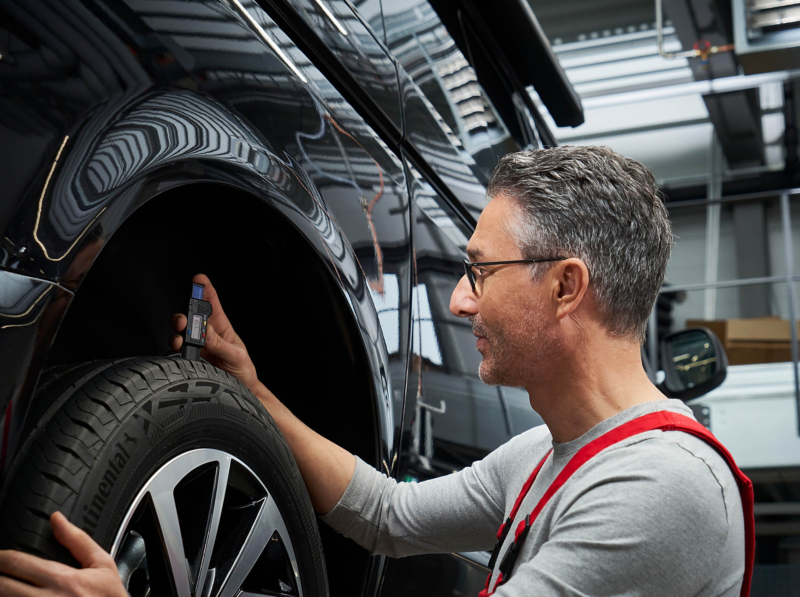 A VW standing next to a raised car with his hand on the tyre