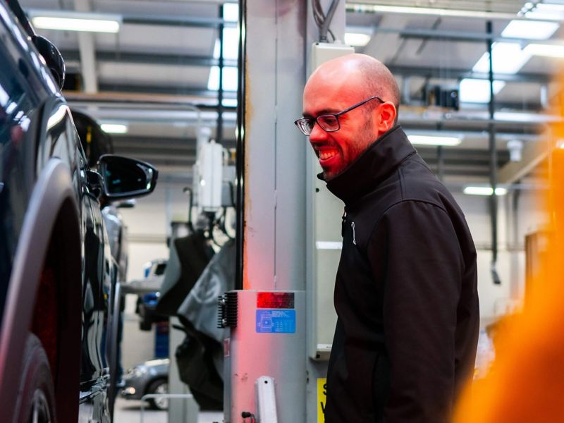 A technician with glasses lit by a red light looks at a VW