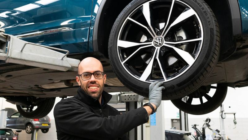 A VW technician wearing a glove with hand on a tyre