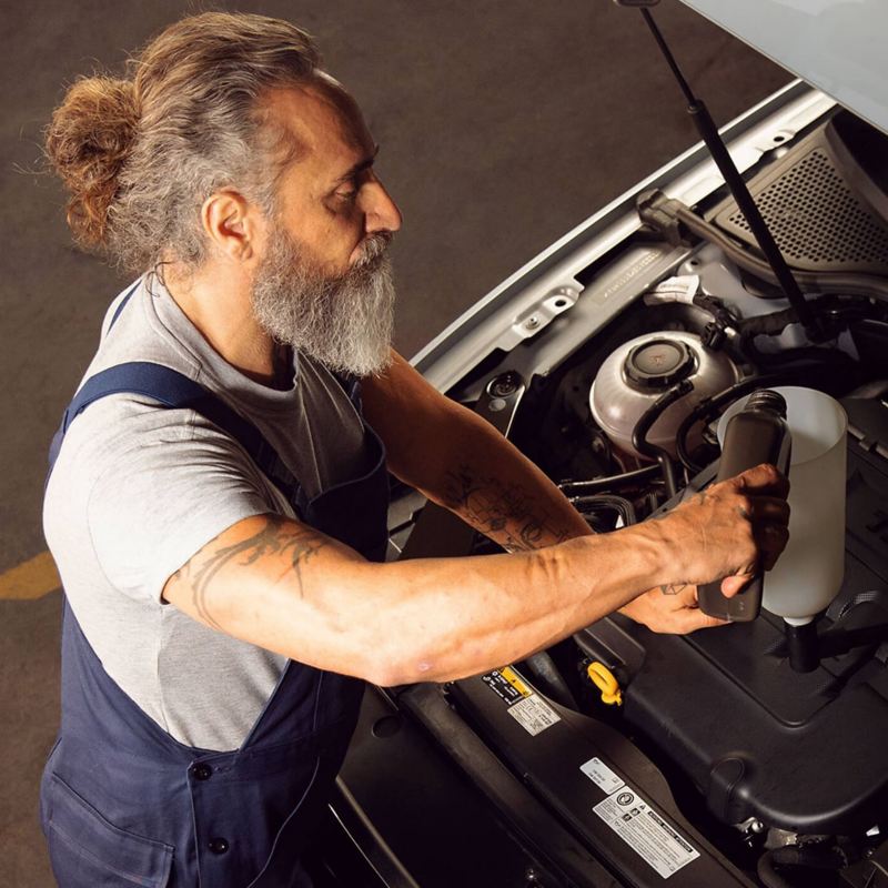 A technician pouring oil into a VW engine