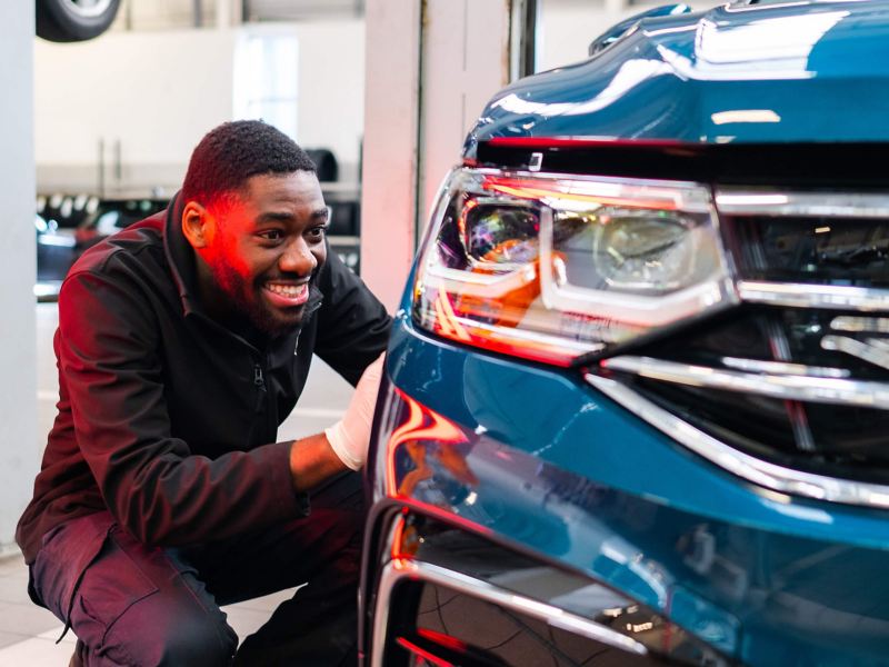 A VW technician inspects the bodywork on a car