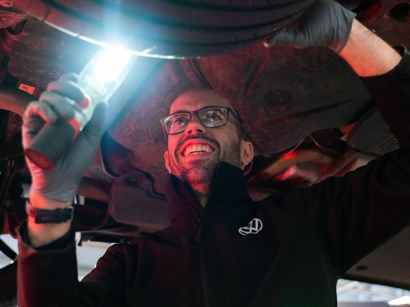 A VW technician inspecting a tyre with a light