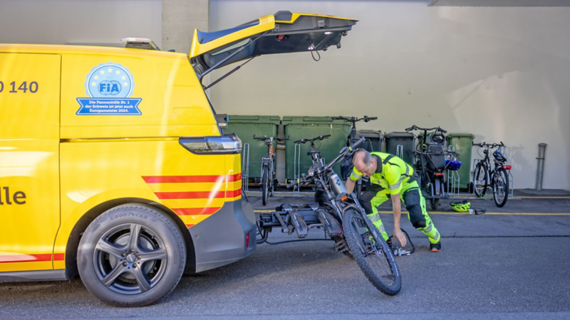 TCS Patrouillenfahrzeug beim Verladen eines Fahrrads auf einen Heckträger.