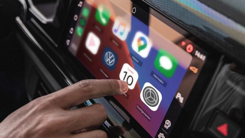 Dedo de conductor elige una aplicación en la pantalla touch de Polo Volkswagen 2024. 