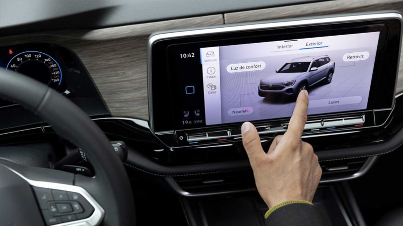 Dedo de conductor toca la pantalla tactil de un auto Volkswagen.