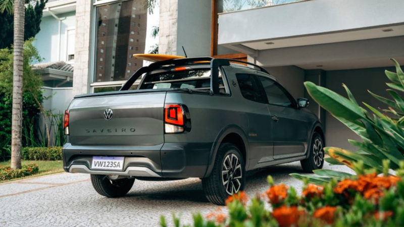 Camioneta Volkswagen Saveiro gris estacionada frente a una casa moderna con diseño elegante y jardín.