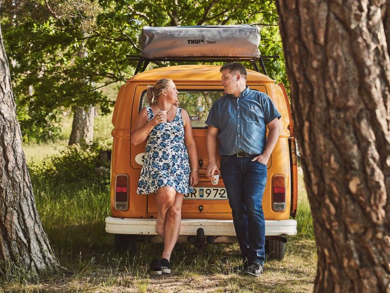 Man och kvinna står vid sin gula VW folkabuss campingbil