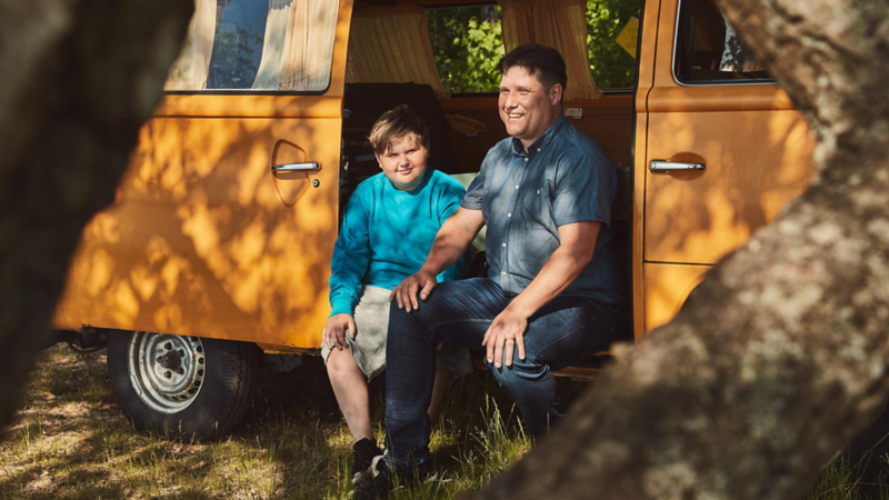 Far och son sitter vid sin VW campingbil