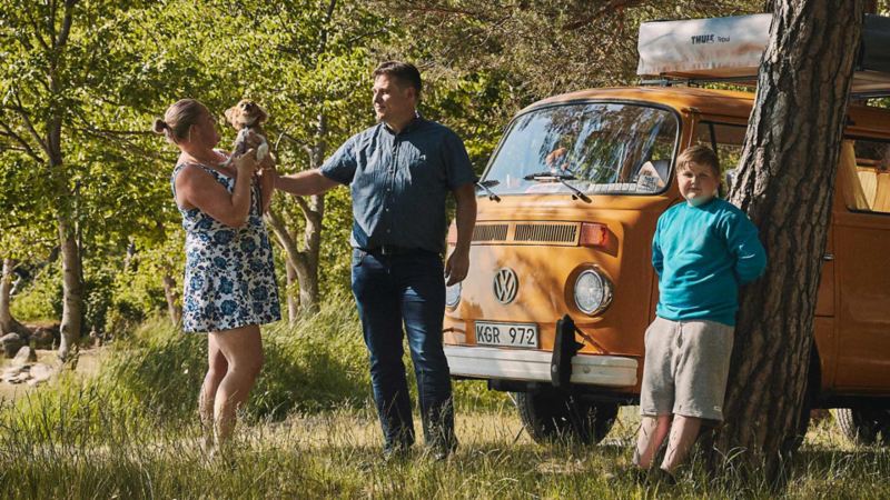 Familj framför en gul VW folkabuss campingbil