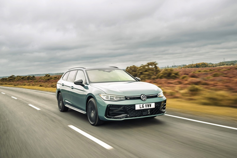 A grey Passat driving down a country road.
